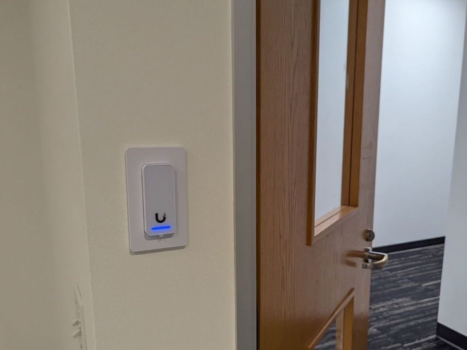A UniFi access reader beside an office door